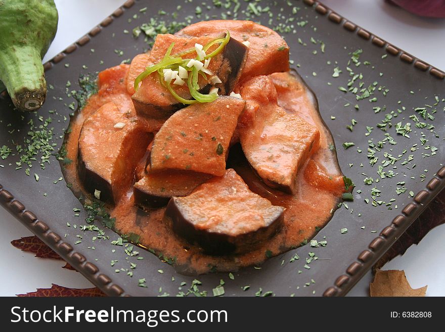 Some fresh aubergines with tomato-sauce on a plate