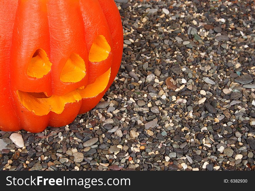 Scary Halloween pumpkin on a pebble background. Scary Halloween pumpkin on a pebble background