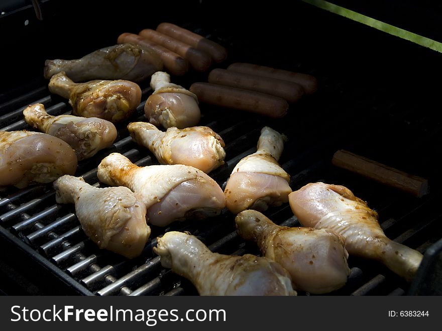 Drumsticks and hot dogs being grilled outside. Drumsticks and hot dogs being grilled outside