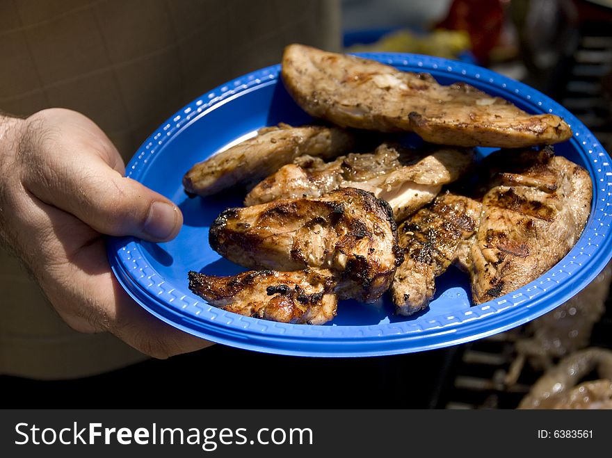 Adult male holding a plate of barbecued chicken. Adult male holding a plate of barbecued chicken