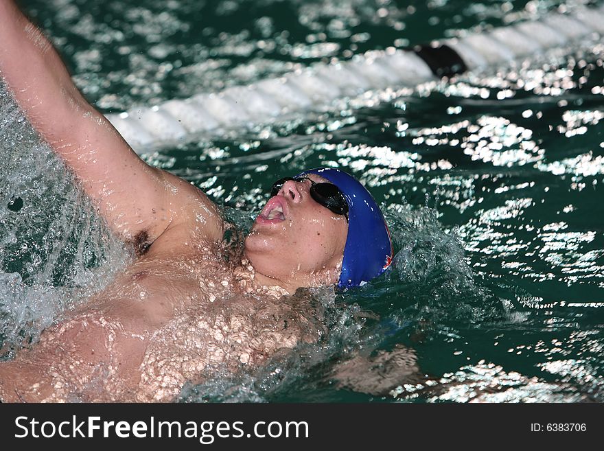 Swimmer in backstroke motion with water splashing over face