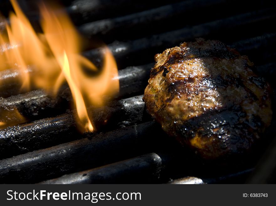 Closeup of a barbecue grills flame with a hamburger patty on it. Closeup of a barbecue grills flame with a hamburger patty on it