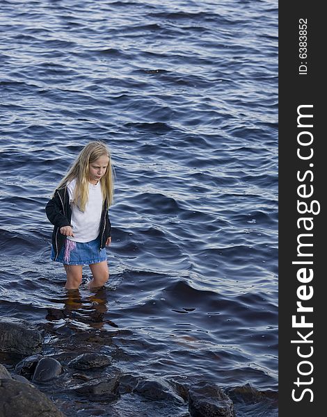 A girl concentrating on not slipping while wading.