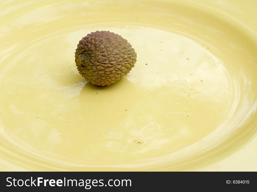 Photo of one lychee on a yellow plate. Photo of one lychee on a yellow plate