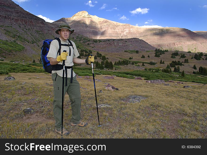 One person walking along trail with brush and mountains in background. One person walking along trail with brush and mountains in background