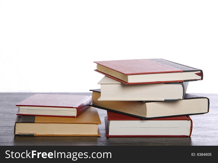 Books are stacked on a desk set against white background. Books are stacked on a desk set against white background.