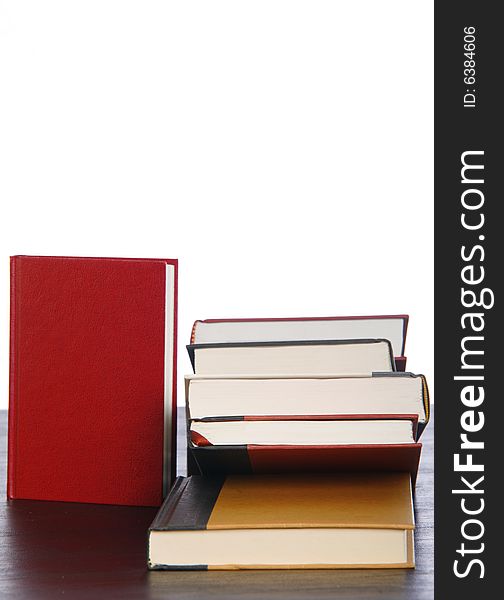 A red book standing near a stack of books isolated against white. A red book standing near a stack of books isolated against white.