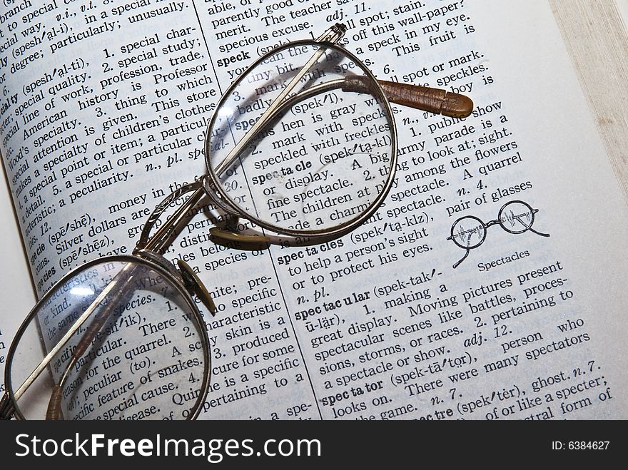Old glasses on the definition of spectacles in an old dictionary. Old glasses on the definition of spectacles in an old dictionary.