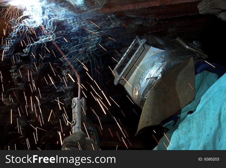 A welder working at shipyard under vessel. A welder working at shipyard under vessel