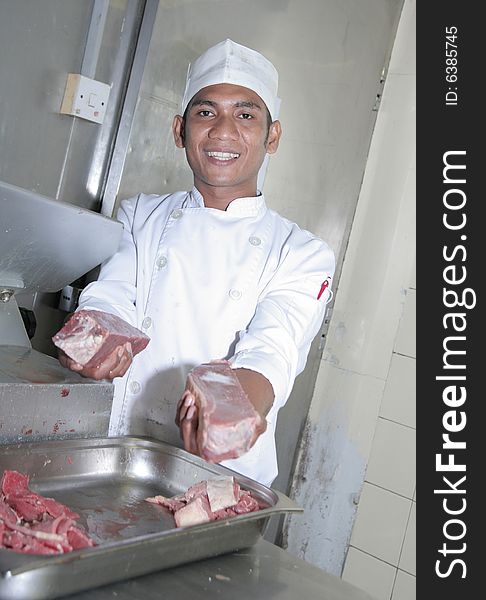 Chef at butcher, cutting meats with cutting machine