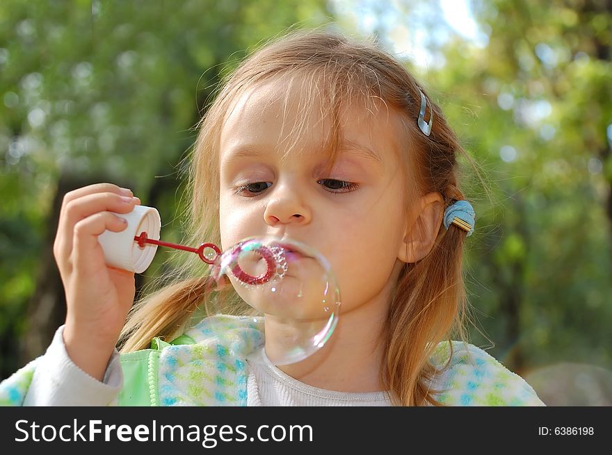 The little girl blowing soap bubbles outdoor. The little girl blowing soap bubbles outdoor