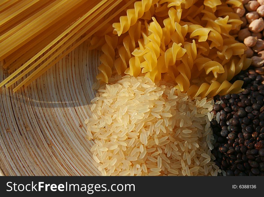 A selection of pulses, rice and spaghetti set on an oval wooden platter. A selection of pulses, rice and spaghetti set on an oval wooden platter