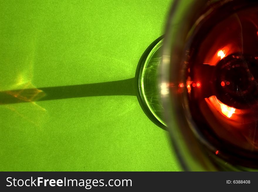 A glass of red wine on a green background taken from an unusual perspective. Cheers!. A glass of red wine on a green background taken from an unusual perspective. Cheers!