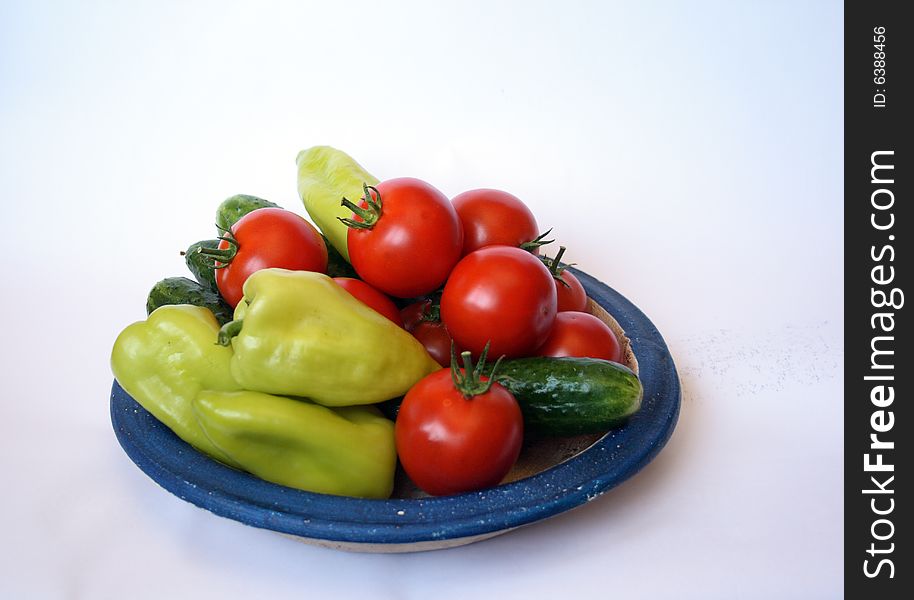 Fresh tomato, sweet peper and cucumber on country style plate isolated on white background