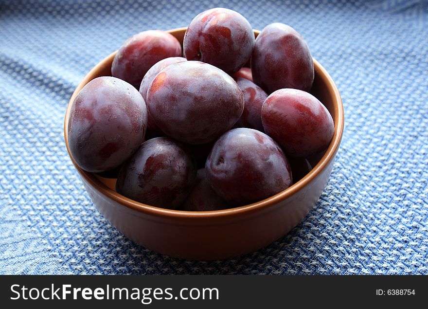 Plums on plate on Blue cloth