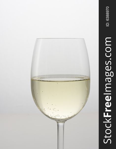 A glass of white wine on a gray background