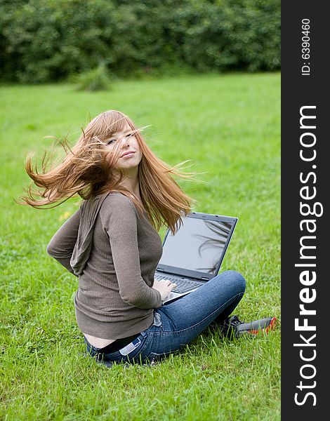 Young girl sitting on the grass with laptop. Young girl sitting on the grass with laptop