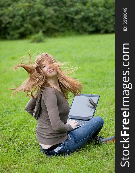 Young girl sitting on the grass with laptop. Young girl sitting on the grass with laptop