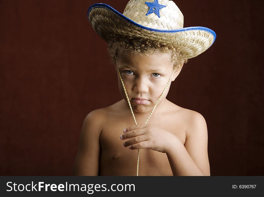 Little boy with curly hair and blue eyes in a sheriff hat. Little boy with curly hair and blue eyes in a sheriff hat