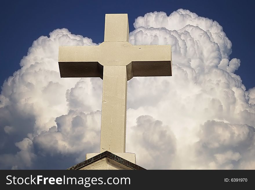 Cross on a background of the blue sky with a huge cloud.