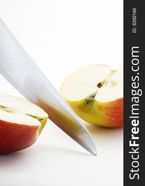 Long bladed kitchen knife cutting through a red apple. Long bladed kitchen knife cutting through a red apple