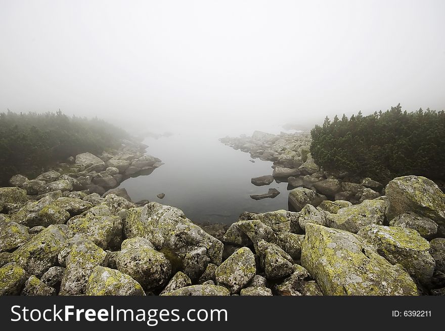 Mountain lake covered in mist in Polish Tatra