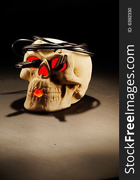 Lit skull on dark background with USB cable put around it in a form of wreath with connectors sticking out from eye holes. Lit skull on dark background with USB cable put around it in a form of wreath with connectors sticking out from eye holes.