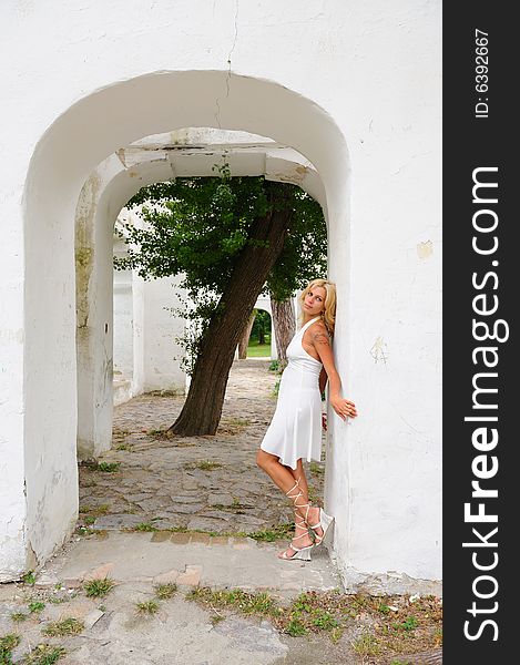 Blond woman in white dress against white wall. Blond woman in white dress against white wall