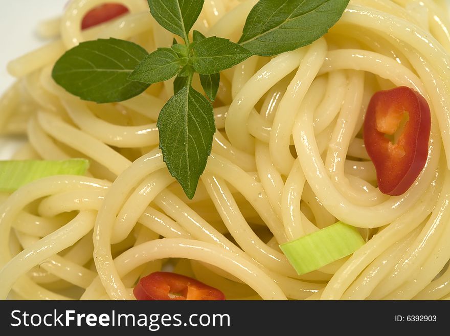 Spaghetti with garnishing of fresh basil leaves.