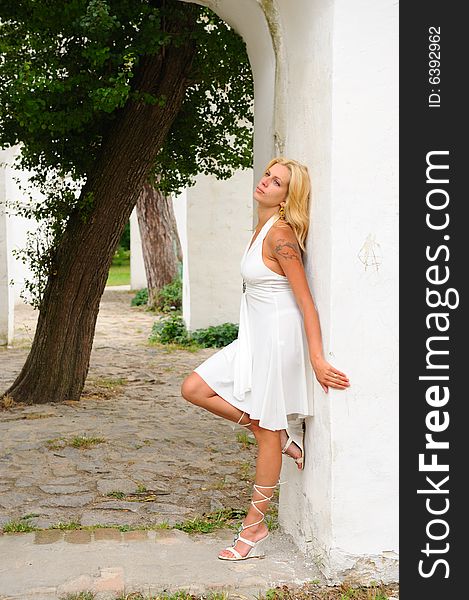 Blond woman in white dress against white wall. Blond woman in white dress against white wall