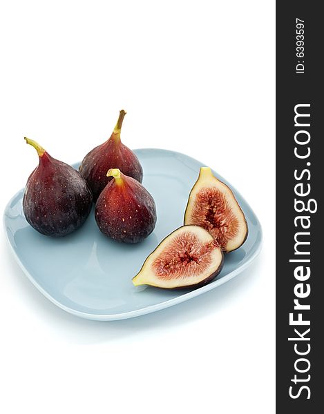 Three whole figs and one sliced one on a square blue plate