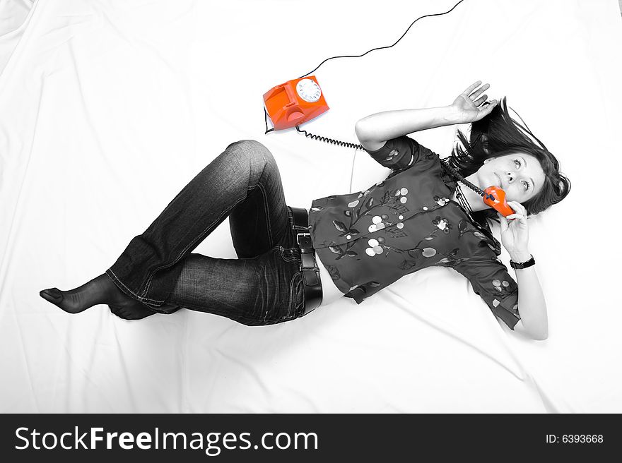 Pretty girl laying on the floor and  talking by orange phone. Pretty girl laying on the floor and  talking by orange phone