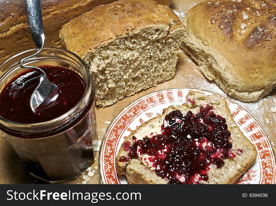 Slice of freshly made grainy bread, with country style plate and board, home made preserve, butter and jam spoon. Slice of freshly made grainy bread, with country style plate and board, home made preserve, butter and jam spoon