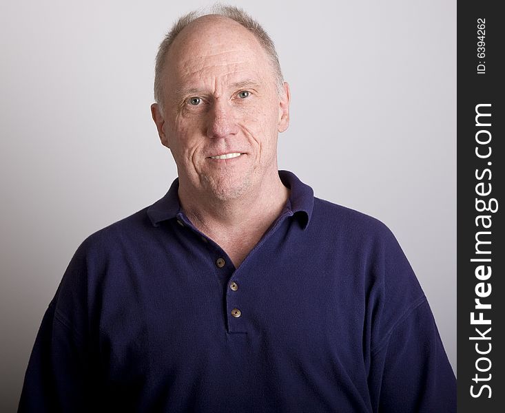 An older bald guy in blue shirt smiling. An older bald guy in blue shirt smiling