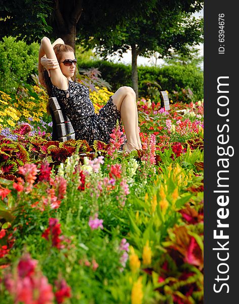 Young girl seating in park among flowers. Young girl seating in park among flowers