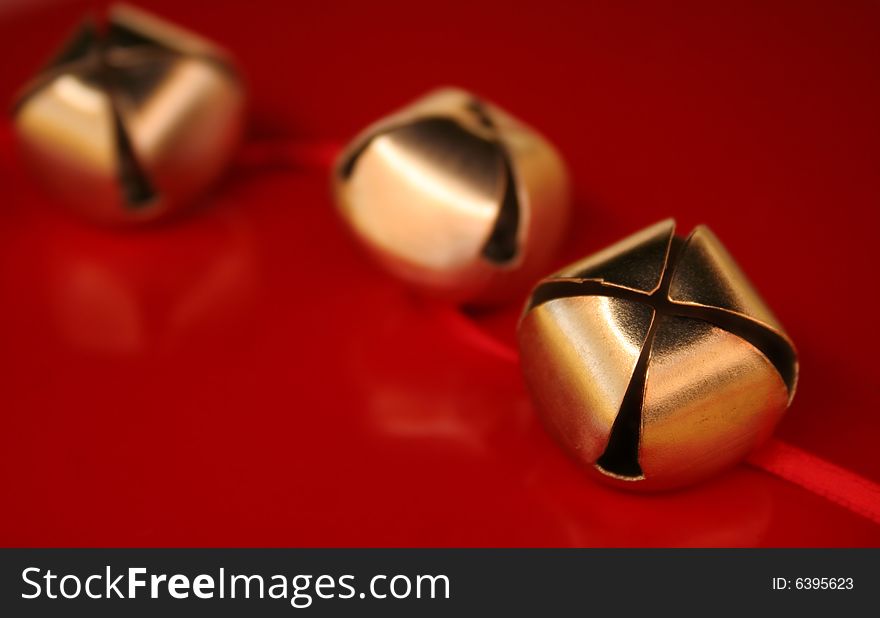 Three gold bells with red ribbon on a red background. Used a shallow depth of field and selective focus. Three gold bells with red ribbon on a red background. Used a shallow depth of field and selective focus.