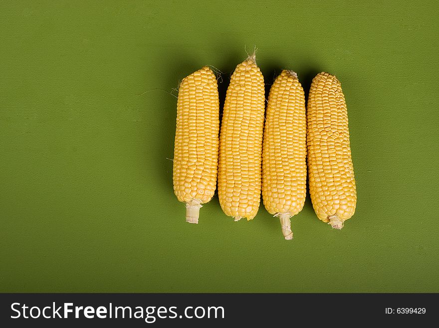 Corn vegetable ear raw on green background. Corn vegetable ear raw on green background