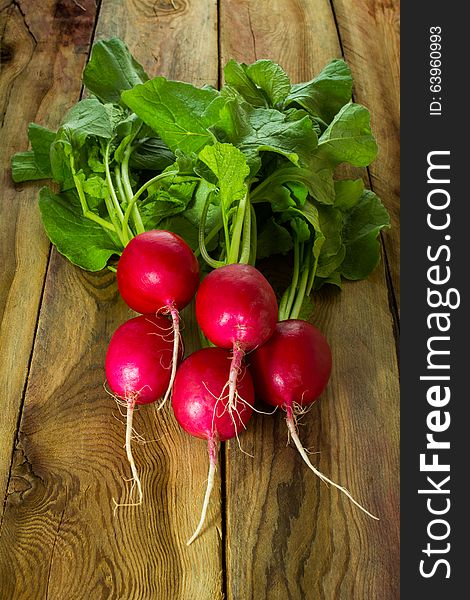 Large bunch of fresh radish on old dark boards, close up, vertical