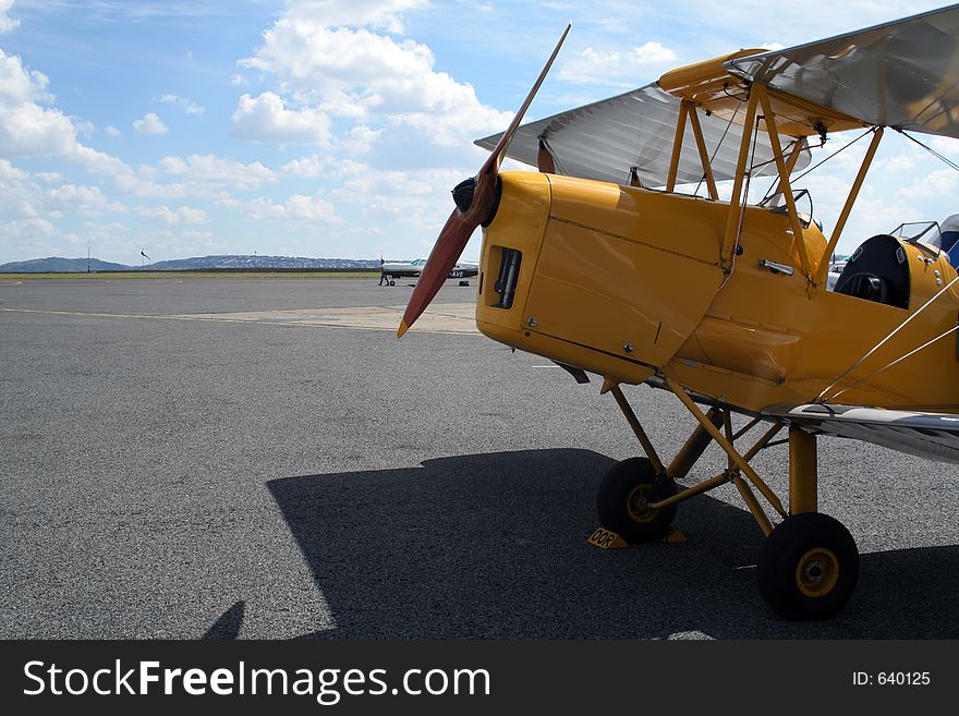 Yellow bi-plane parked on the runway