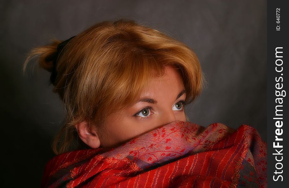 The woman in a red scarf on a grey background. The woman in a red scarf on a grey background
