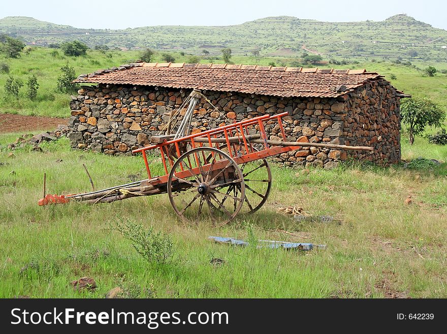 Rural stone and mud hut and painted bullock cart resting in meadow, western India. Rural stone and mud hut and painted bullock cart resting in meadow, western India