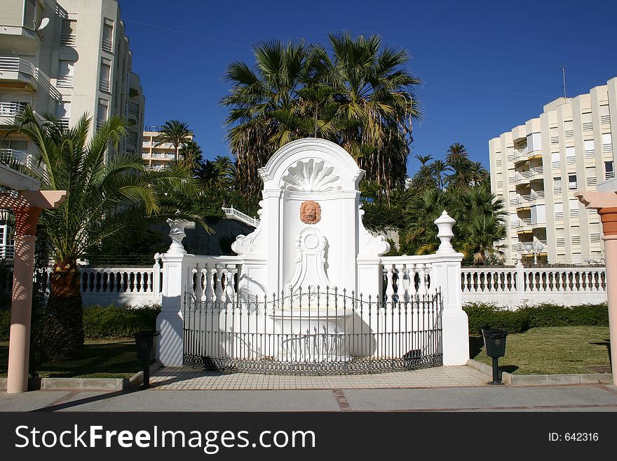 Ornate water fountain set against trees and blue sky