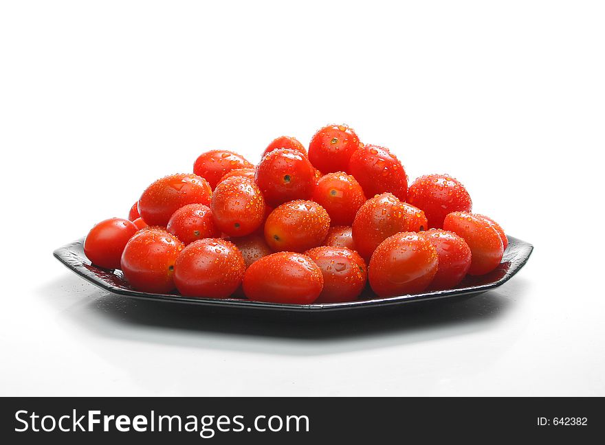 Lot of cherry tomatoes with drops over a black plate. Look at my gallery for more fresh fruits and vegetables.