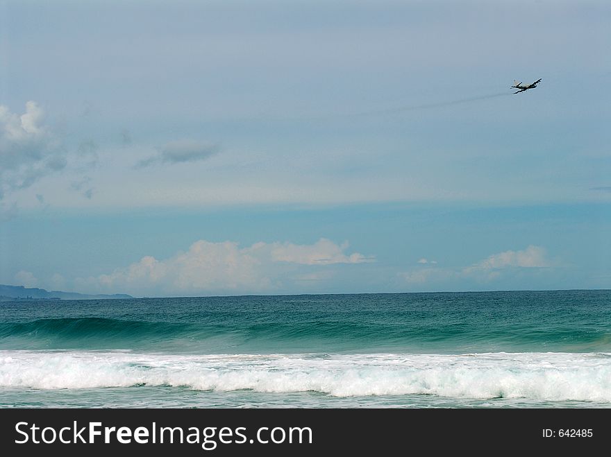 A military plane flying over the beach in hawaii