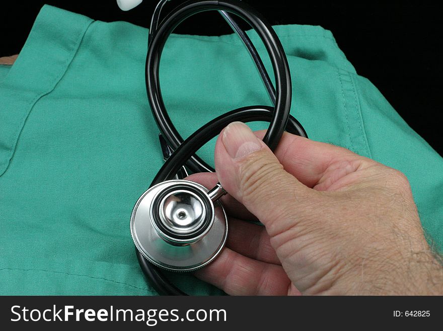 Hand holding stethoscope over smock with black background. Hand holding stethoscope over smock with black background.