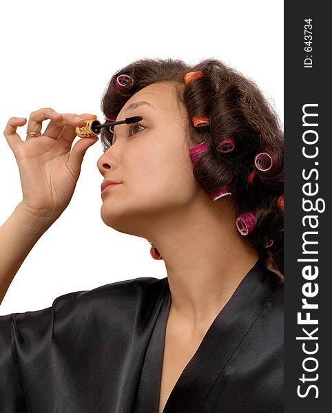 A girl in hair curlers is making herself up with Indian ink. A girl in hair curlers is making herself up with Indian ink