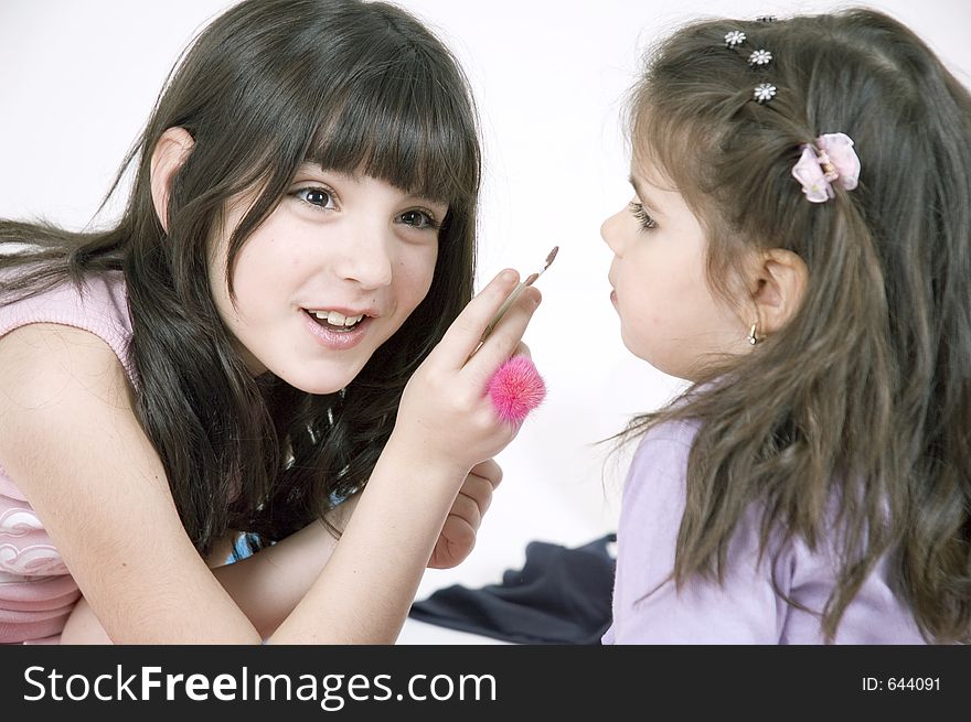 Little girl applying lipstick on her little sister's lips. Little girl applying lipstick on her little sister's lips
