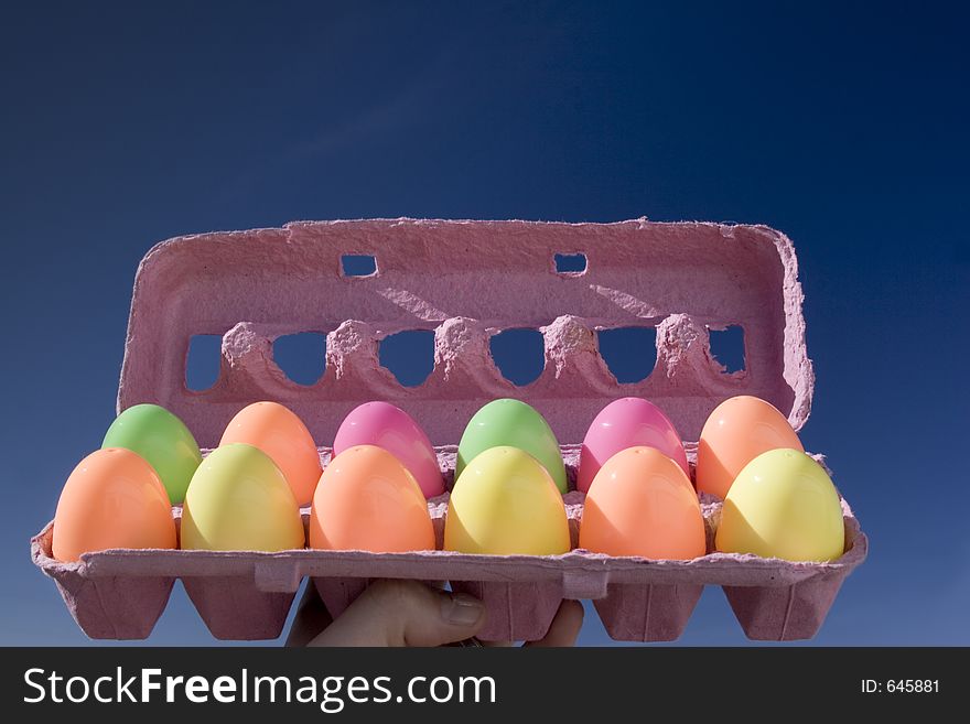 An egg carton with 12 colorful eggs in it. An egg carton with 12 colorful eggs in it