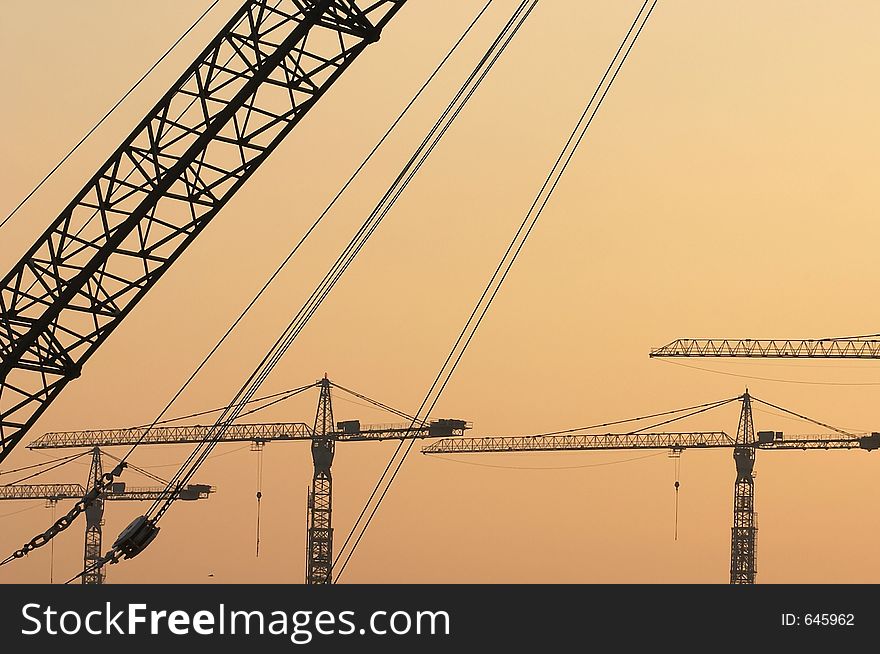 Crane booms against sunset