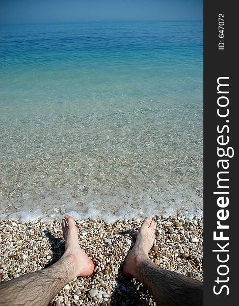 Looking at feet in water sand and stones of Southern Italy. Looking at feet in water sand and stones of Southern Italy